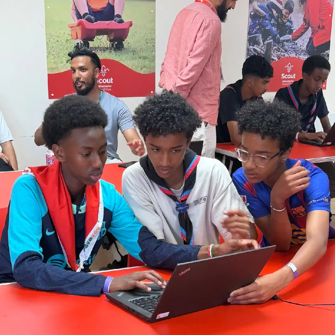Three Scouts collaborating on a project on a laptop